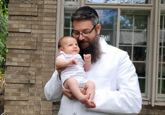 Rav Eliyahu Weisman in white holding a baby