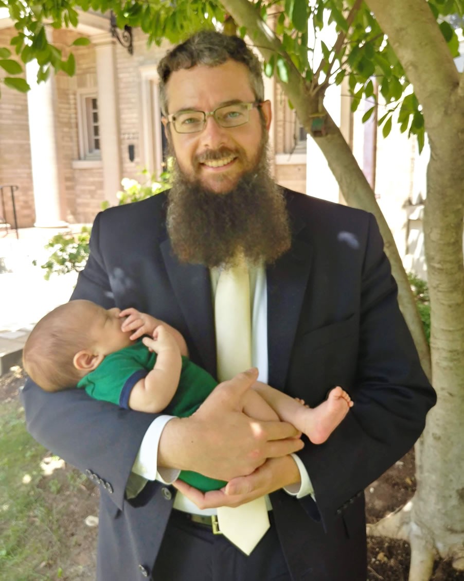 Rav Eliyahu Weisman holding a newborn baby