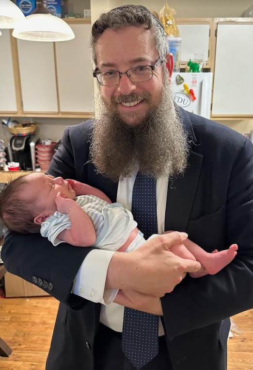 Rav Eliyahu Weisman holding a newborn baby