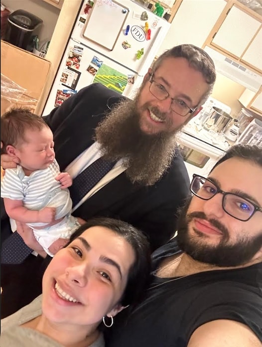 Rav Weisman with a newborn and his happy parents