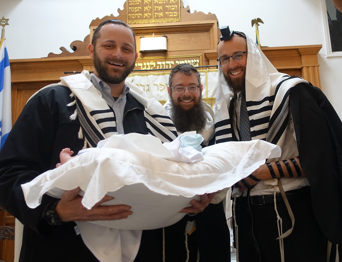 Rav Weisman with fellow Mohelim carrying a baby on a bris pillow